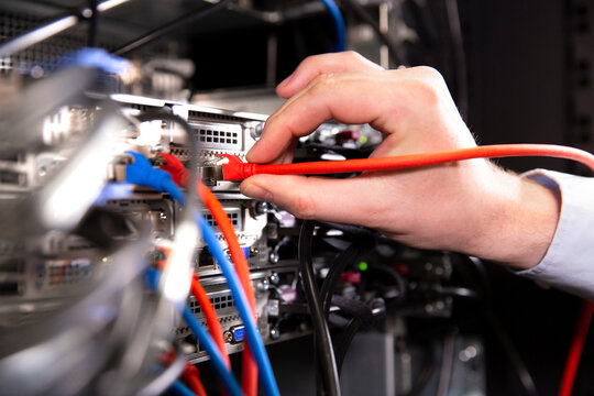 Close-up of male engineer examining network connection plug in data center