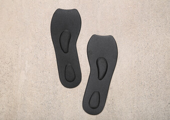 Black orthopedic insoles on grey grunge background