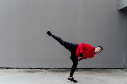 Sportsman practicing kickboxing while standing against wall