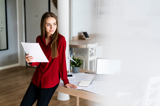 Woman in office holding paper with wind turbine model on table
