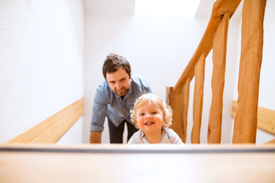 Father with little boy on wooden stairs at home