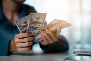 A person is holding a stack of money in their hand