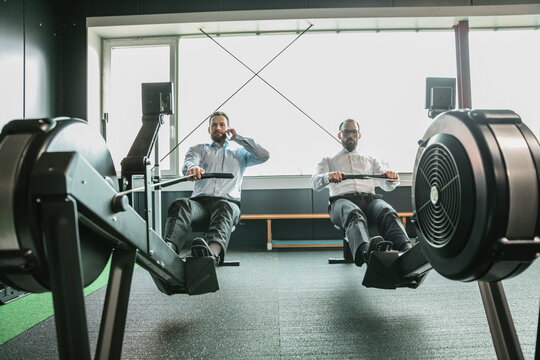 Businessmen training in gym, while making a phone call
