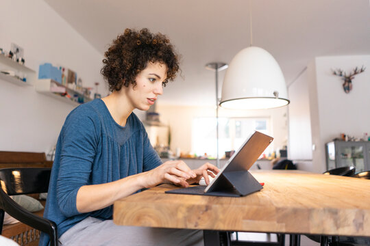 Young woman sitting at table, using digital tablet