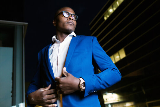 Young businessman wearing blue suit jacket, ooking sideways at night