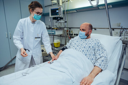 Doctor connecting patient to pulse tracer in hospital room