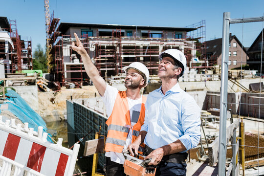 Smiling construction worker talking to man on construction site