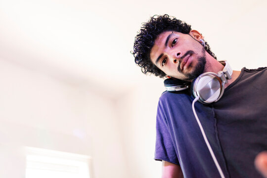 Confident young male DJ listening through headphones at recording studio