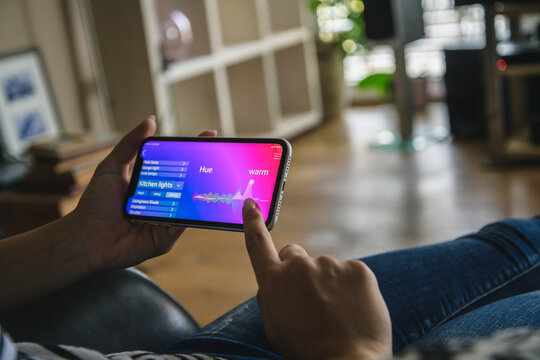 Young woman with smartphone with smart home control functions