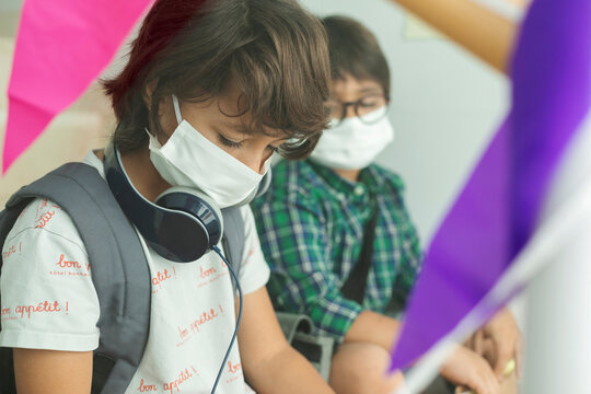 Close-up of boys wearing masks maintaining social distance while sitting in school