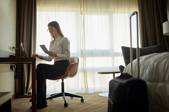 Businesswoman sitting at desk in hotel room using laptop