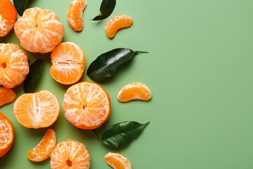 Sweet tangerines with leaves on green background