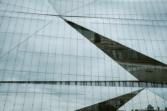 Modern geometric glass facade architecture with diagonal lines pattern and reflection creating abstract urban corporate texture background for design