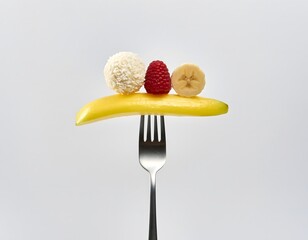 Fresh fruit arranged on a banana slice on a fork.