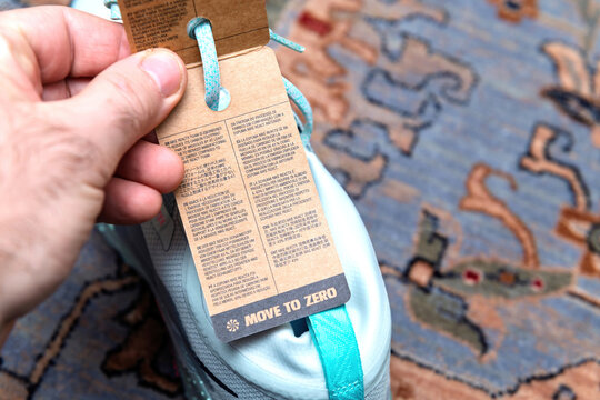 Paris, France - Jan 11, 2026: Close-up POV of hand holding Nike footwear product label with recycling information and Move to Zero sustainability text. Unboxing new athletic shoes.