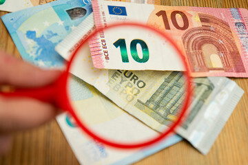 Euro banknotes under a magnifying glass. The concept of inflation, poverty, economic crisis. The concept of saving money. Finance, business, investment. Saving savings at home. 