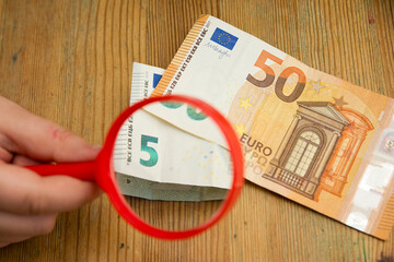 Euro banknotes under a magnifying glass. The concept of inflation, poverty, economic crisis. The concept of saving money. Finance, business, investment. Saving savings at home. 