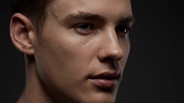 Intense portrait of a young man with a focused gaze and noticeable facial marks, captured with dramatic lighting to emphasize his powerful presence and reflective mood