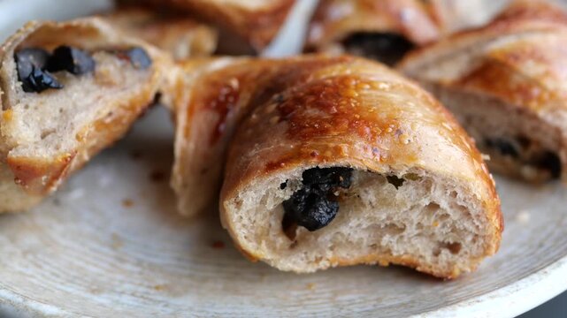 Close up view of freshly baked olive bread on white plate with golden brown crust and soft interior texture