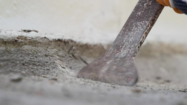Worker using powerful industrial jackhammer with flat chisel to remove concrete surface during renovation project close up footage