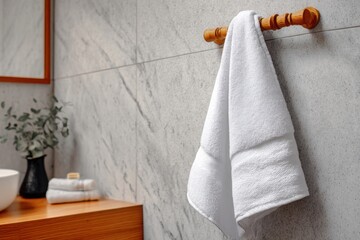 Close up of soft white towel hanging on metal holder against gray textured bathroom wall, showcasing clean modern home interior.