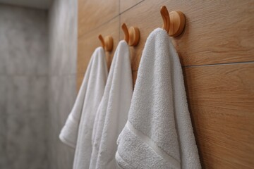 Close up of soft white towel hanging on metal holder against gray textured bathroom wall, showcasing clean modern home interior.