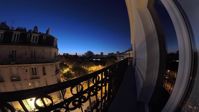 Wide-angle from a balcony showing dawn breaking over the rooftops of Paris, France. Night to day timelapse