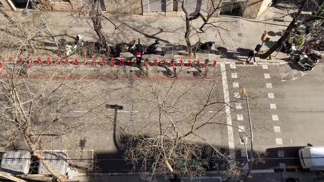 Vista desde balc&oacute;n de una calle de la ciudad, con paso de peatones, coches circulando y aparcamiento de bicicletas. D&iuml;a soleado y con mucho viento