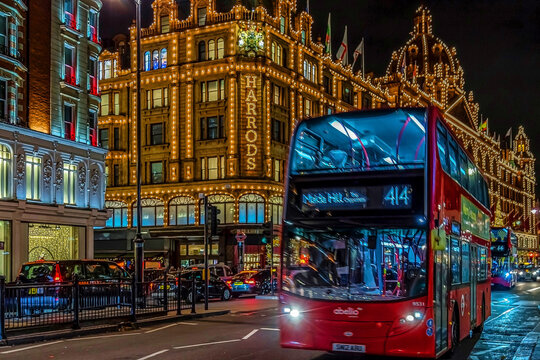 Night view with red double decker bus on moving in front of Harrods, the biggest luxury department store from the Europe. London, UK
