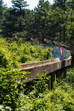 Sarajevo, Bosnia and Herzegovina - 16 June 2025: View of the decaying, graffiti-covered bobsleigh track, a stark contrast of urban decay against the vibrant green forest backdrop.
