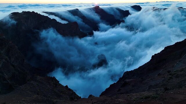 Aerial drone footage revealing the sunrise breaking through over clouds in Roque de los Muchachos, La Palma