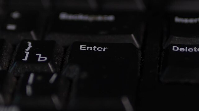 A moody, shallow depth-of-field close-up of a black computer keyboard. The &ldquo;Enter&rdquo; key is centered and most readable