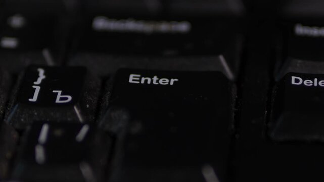 A moody, shallow depth-of-field close-up of a black computer keyboard. The &ldquo;Enter&rdquo; key is centered and most readable