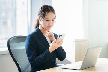 オフィスでスマホを持つビジネスウーマン