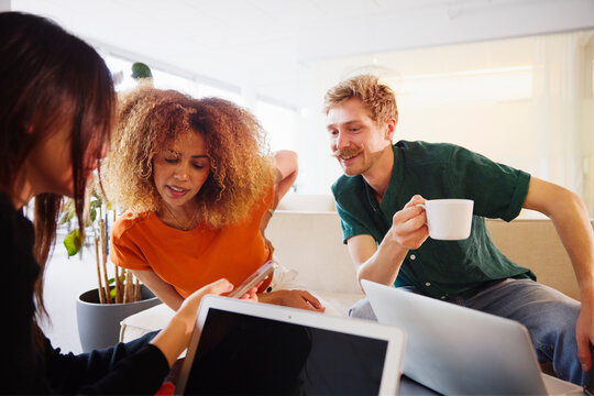 Multiracial male and female business employees looking in smart phone held by coworker at office