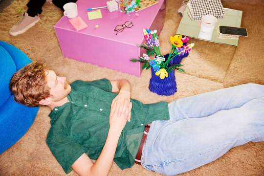 High angle view of male entrepreneur lying down on carpet while relaxing during break time in office