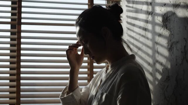 Silhouette of woman touching her forehead