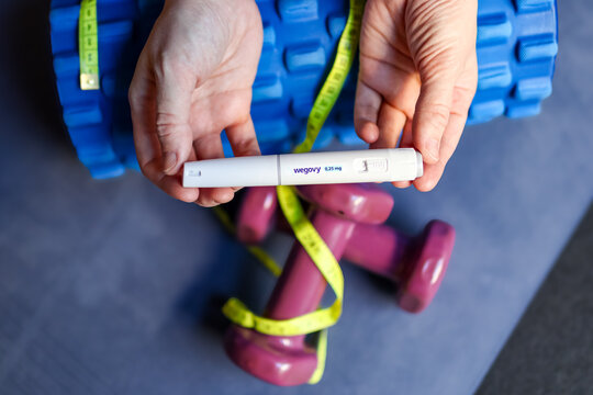 Wroclaw, Poland. January 5, 2026. Wegovy (semaglutide) weight loss injection pen held above dumbbells, foam roller and measuring tape