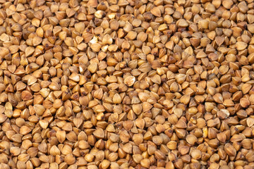 Fototapeta premium a dense, uniform field of raw buckwheat groats, highlighting their angular shapes and earthy brown color.