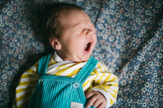 Directly above shot of cute baby yawning while lying on bed