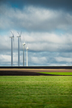 Tall wind turbines in beautiful field against sky