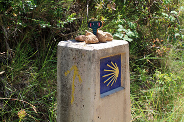 Camino sign with scallop in foreground and Monjardin hill with castle in background on Camino de Santiago Frances in Navarra Spain July 2024 © leodaphne