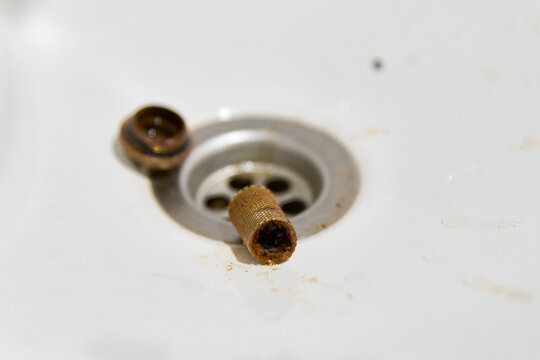 Removal of clogged strainer filter mesh from sink drain in bright white environment