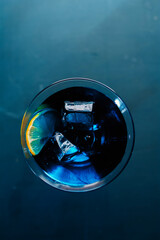 Electric blue cocktail in elegant martini glass with ice cubes and fresh lime slice. Moody dramatic lighting, sophisticated top-down view &mdash; perfect for luxury bar, party and summer refreshment concept