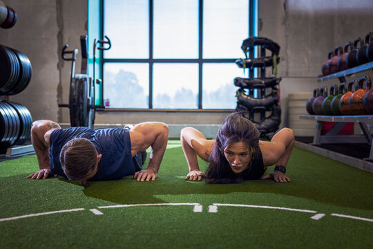 Male and female athletes doing push ups on gym floor