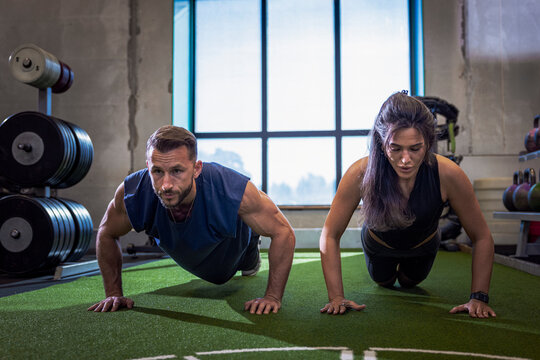 Determined athletes doing push-ups while working out in gym