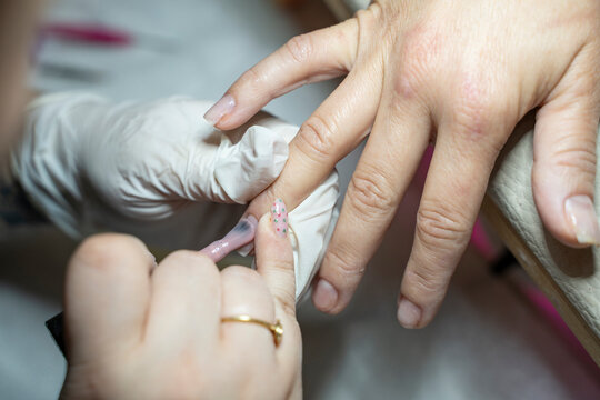 Manicurist applying bulder gel to client's nails in beauty salon Stock Photo