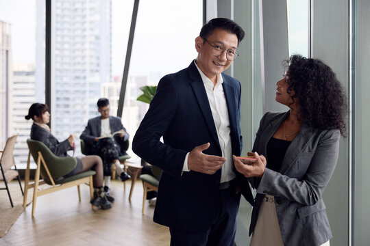 Portrait of smiling male manager standing next to female colleague at office