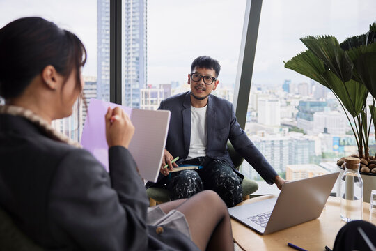 Young male entrepreneur sitting with colleague in office meeting