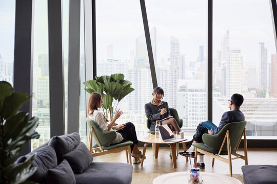 Group of young entrepreneurs discussing strategies while sitting on chairs at office